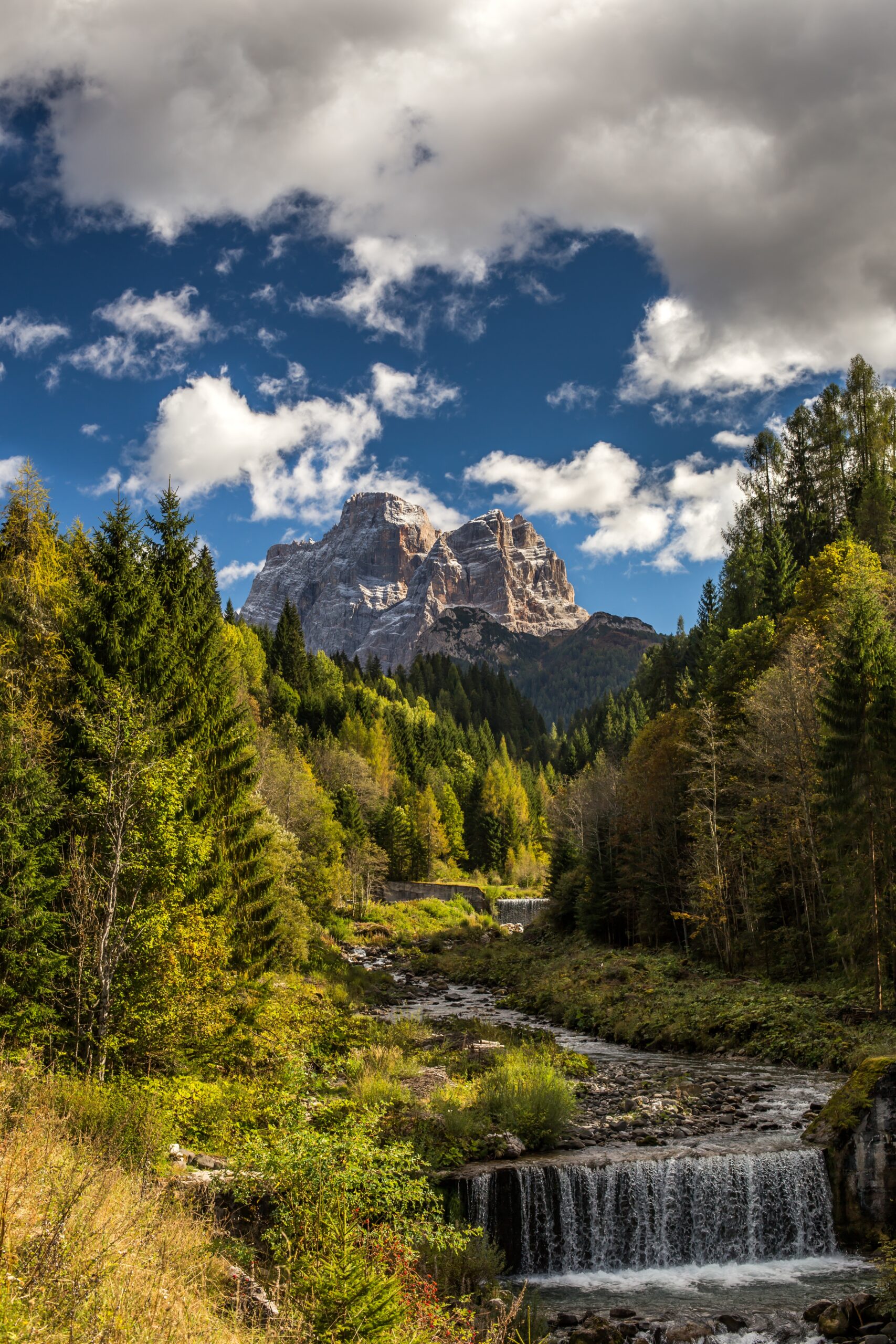 Vertical picture of a river in a forest with rocks under a cloudy sky on the background in Italy A vertical picture of a river in a forest with rocks under a cloudy sky on the background in Italy